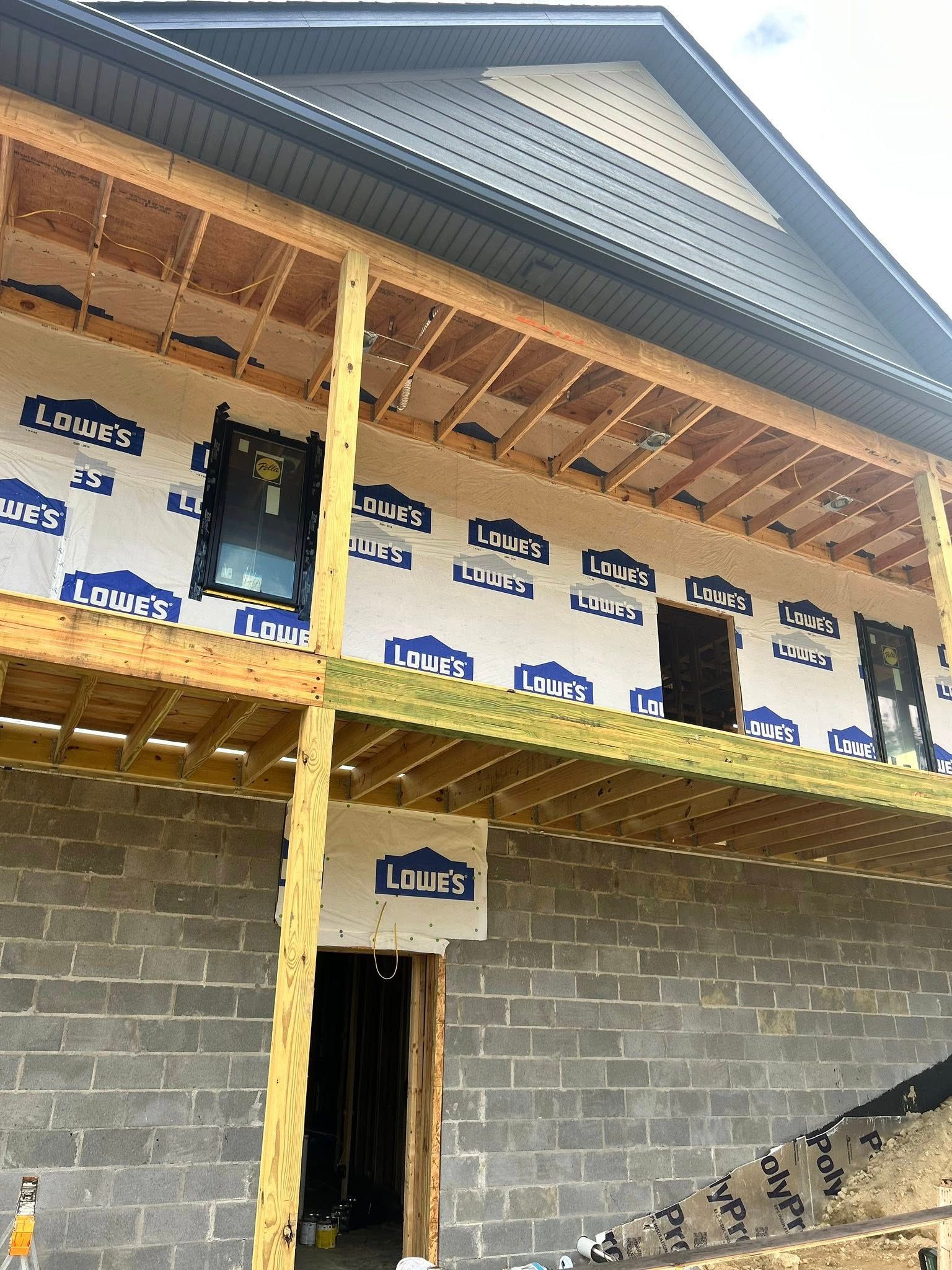 Construction site of a two-story building with a wooden deck and cinder block foundation.