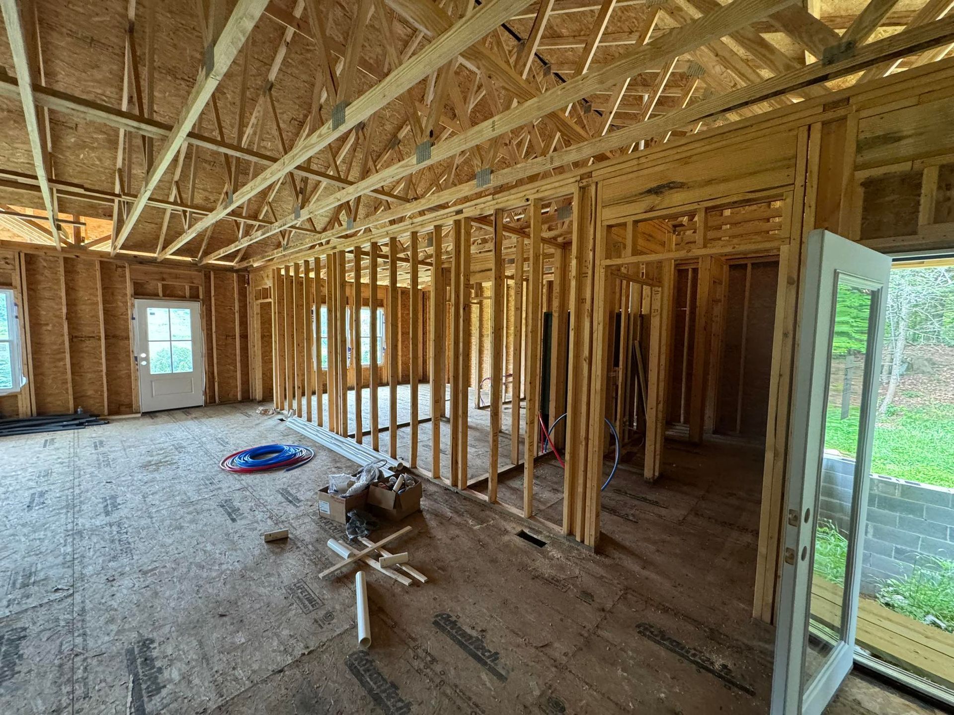 Interior view of a house under construction with exposed wooden framing and doorways.