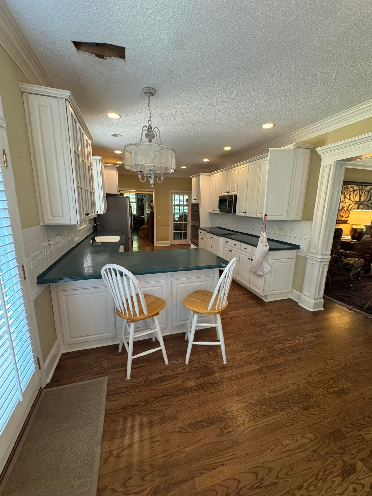 Kitchen with white cabinets, blue countertop, wood floor, two stools.