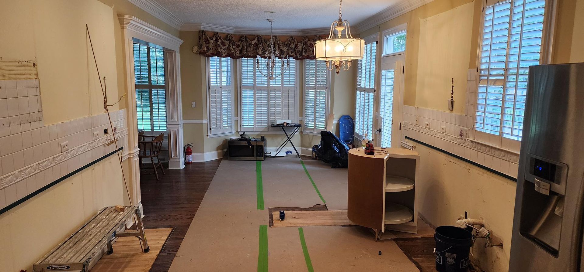 Interior room during renovation, beige walls, exposed drywall, windows, and a partially built cabinet.