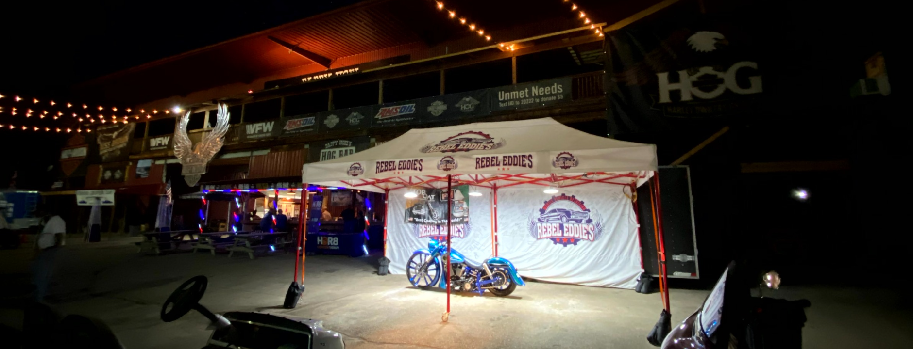 a motorcycle is parked in front of a tent at night .