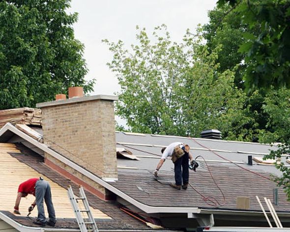 two men are working on the roof of a house