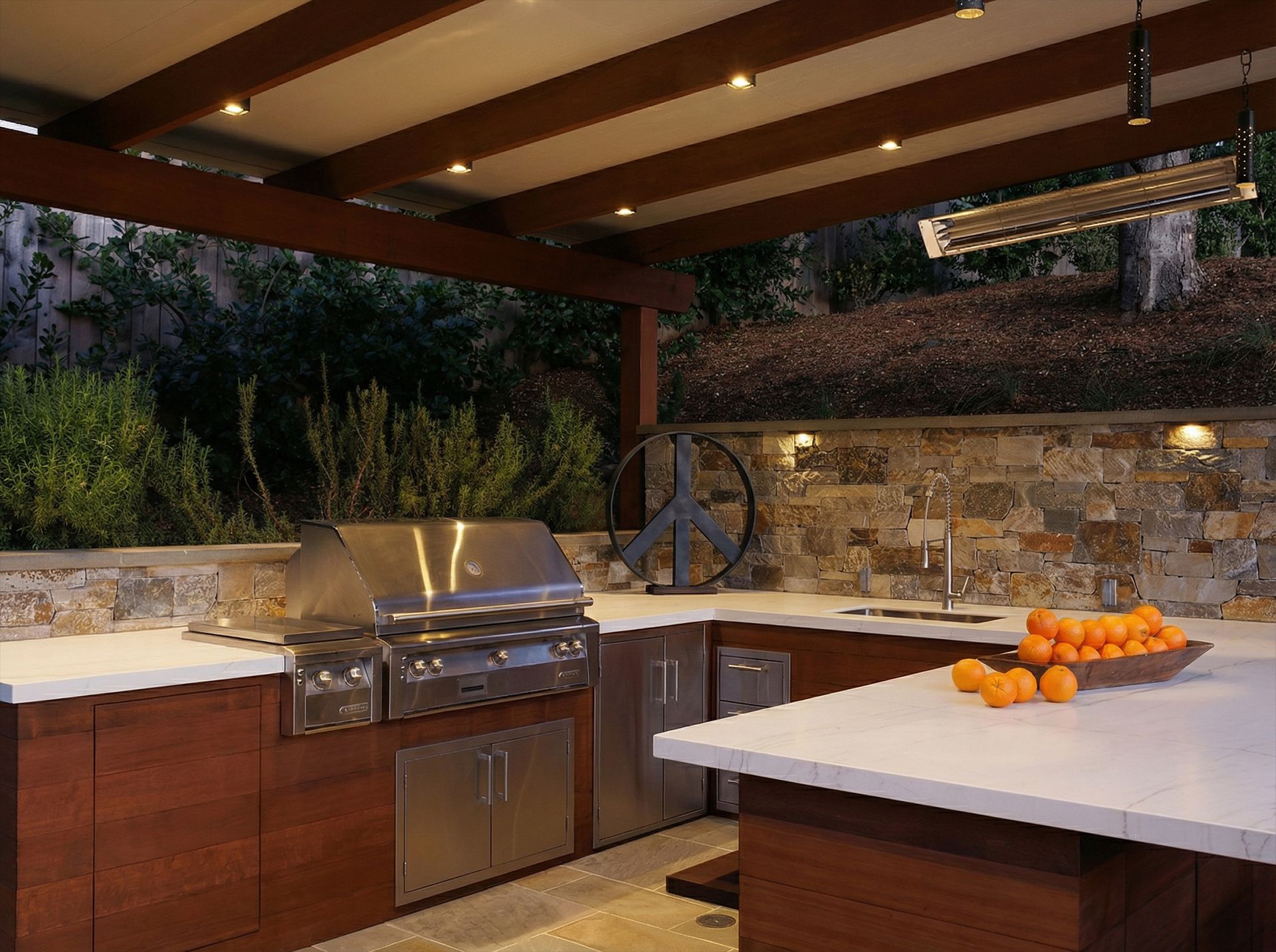 Outdoor kitchen with grill, stone wall, and countertop with oranges.
