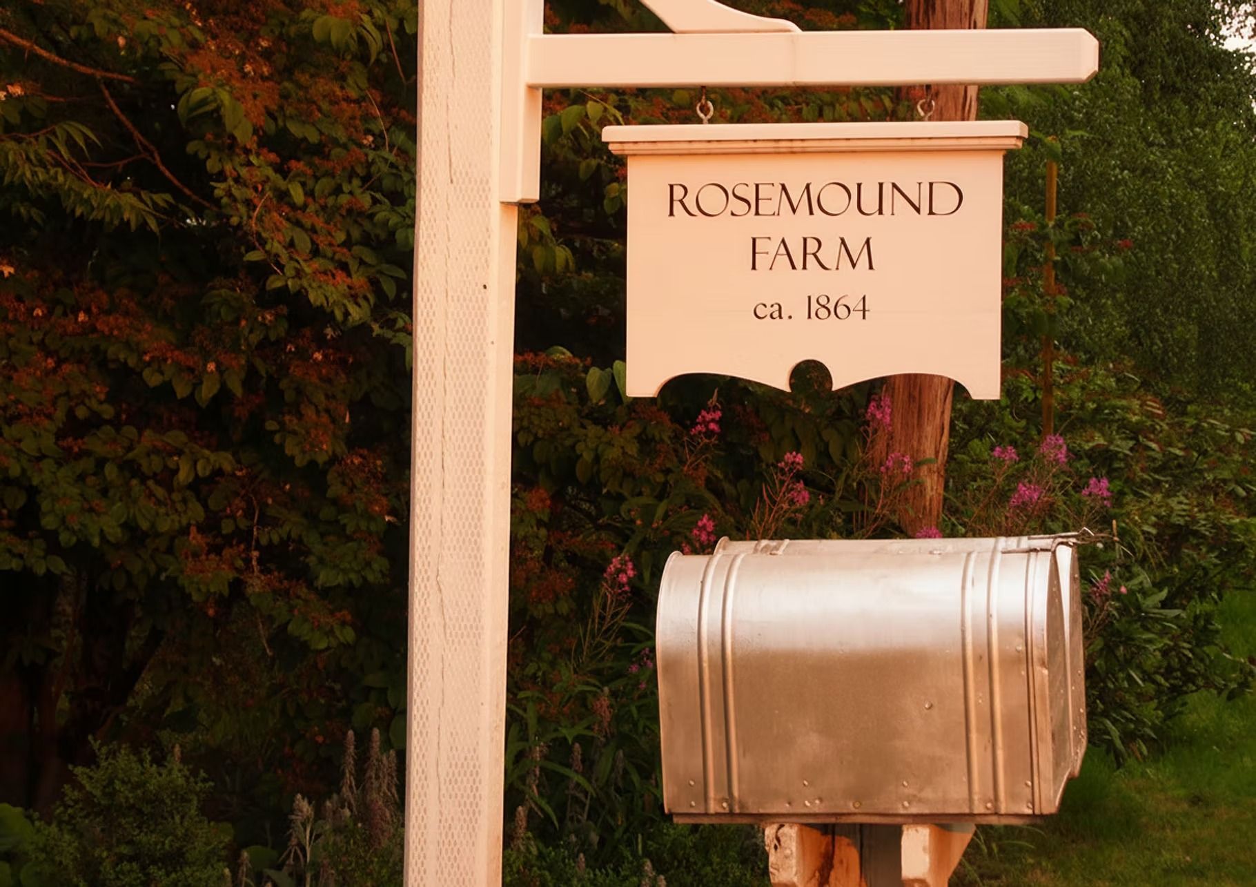 White Rosemound Farm sign and silver mailbox; trees in background.