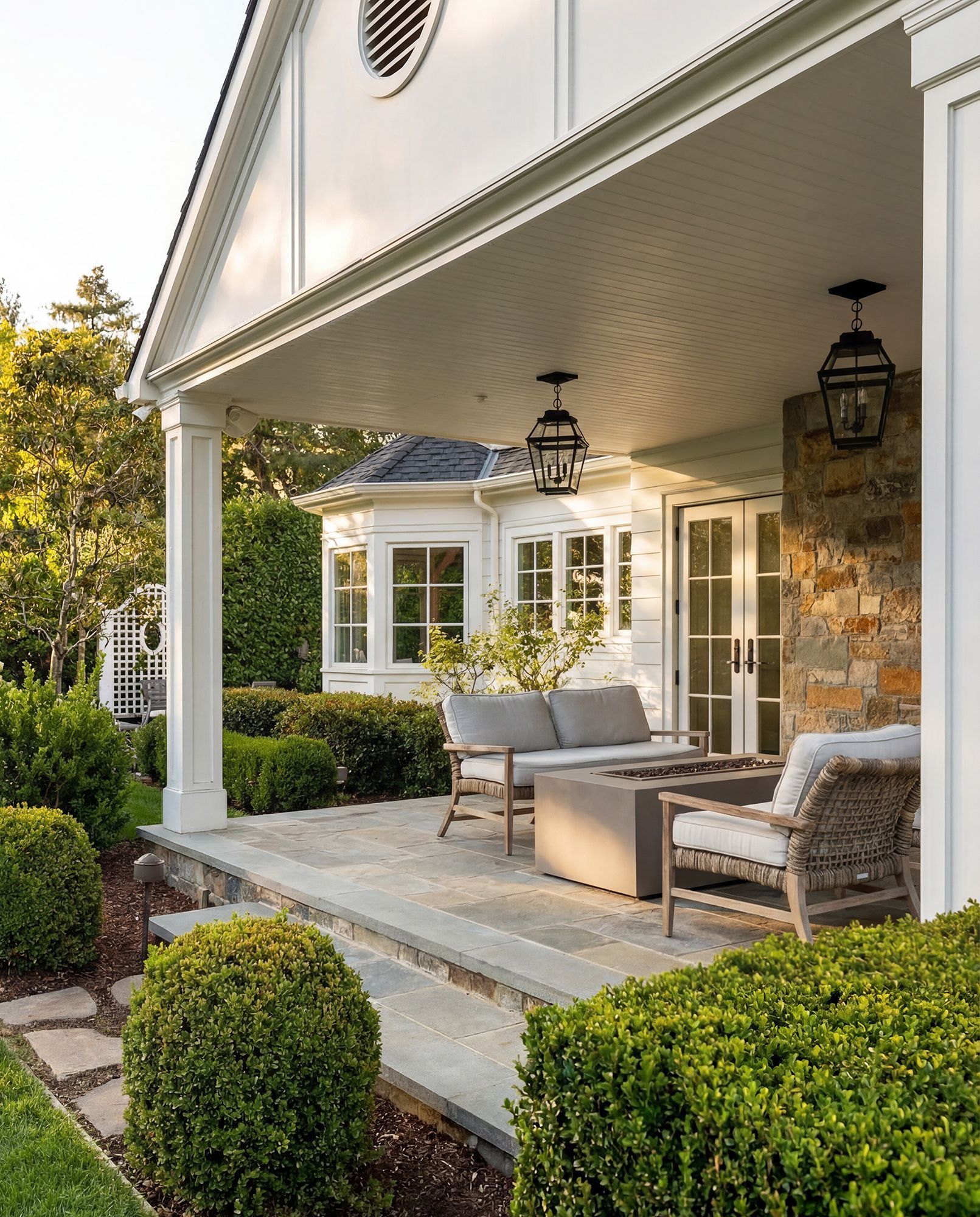 Covered porch with seating, hanging lanterns, and stone accents.