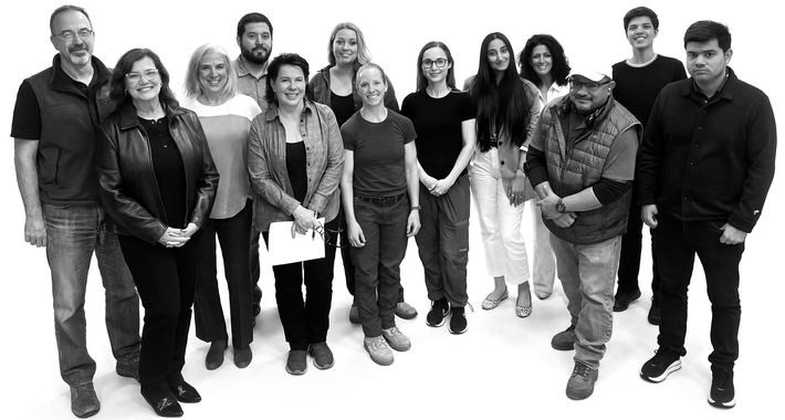 Group of people standing together, looking at the camera against a white backdrop.