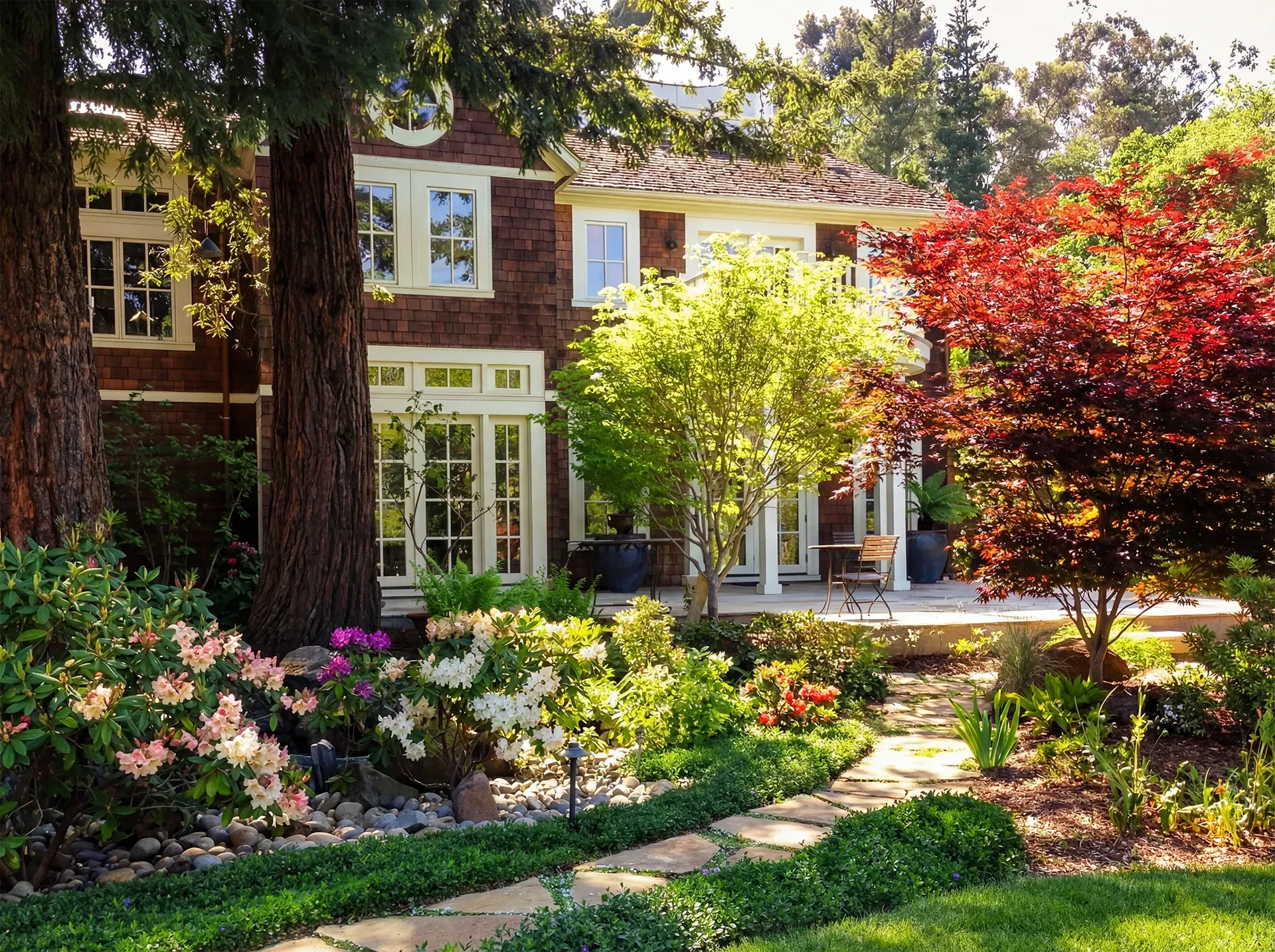 House with lush garden, path leading to the entrance, trees with red and green foliage.