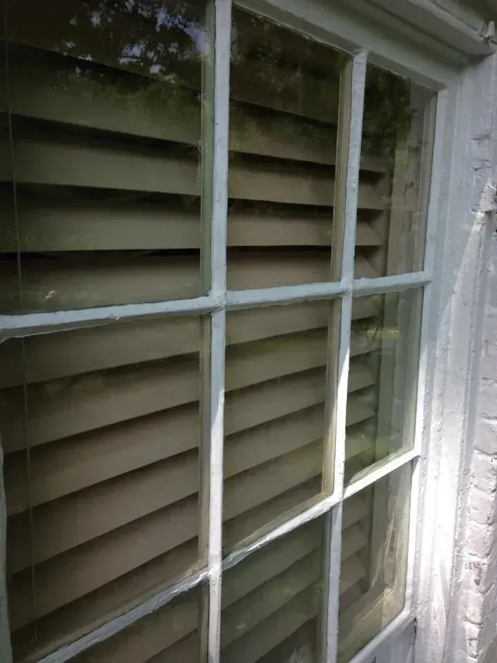 Window with six panes, revealing wooden blinds behind the glass.