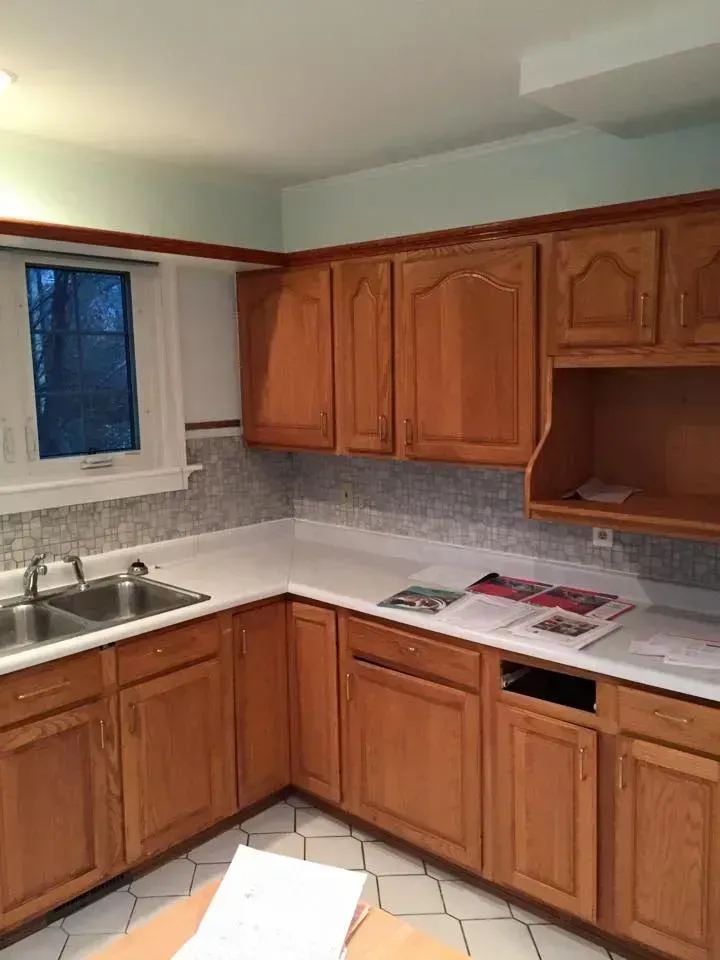 Kitchen with light-colored cabinets, white countertops, and a patterned backsplash.