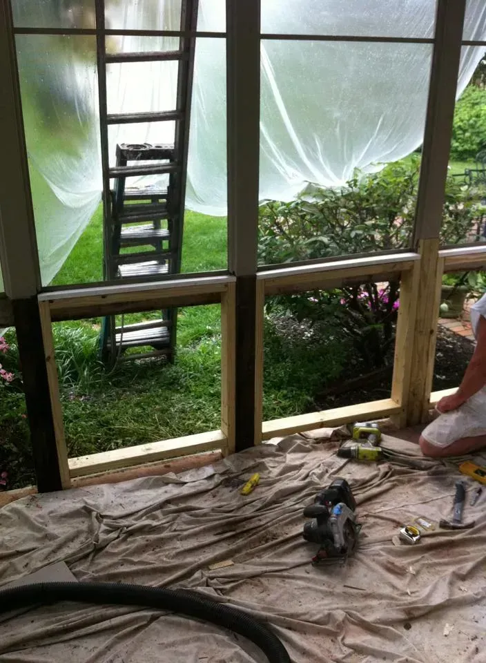 A ladder, plastic sheeting, and wood framing are visible with tools and materials.