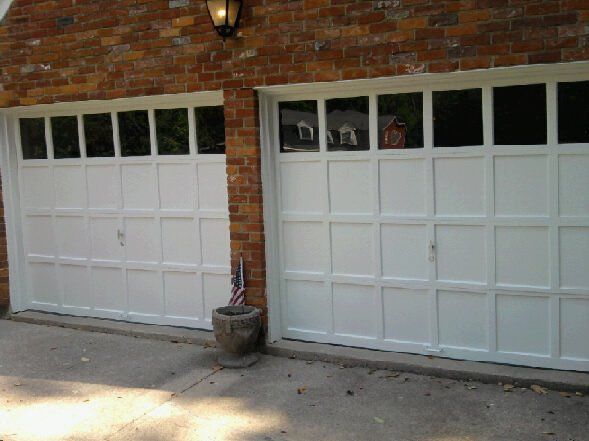 A pair of white garage doors on a brick building.