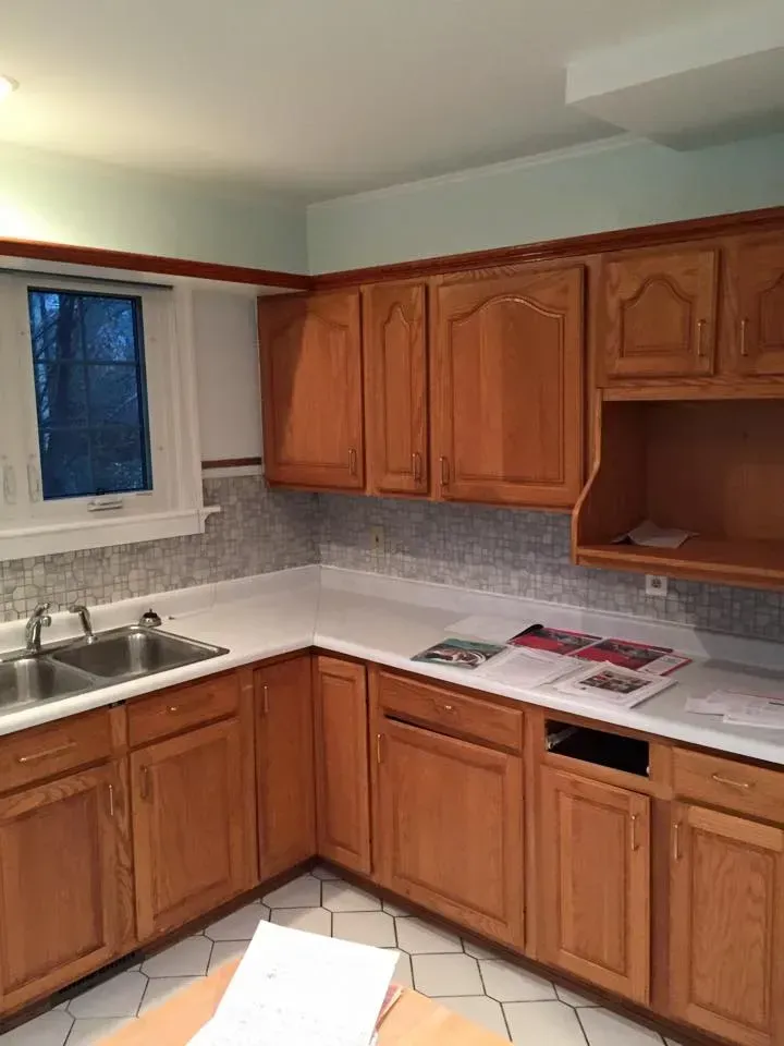 A kitchen with wooden cabinets , a sink , and a window.