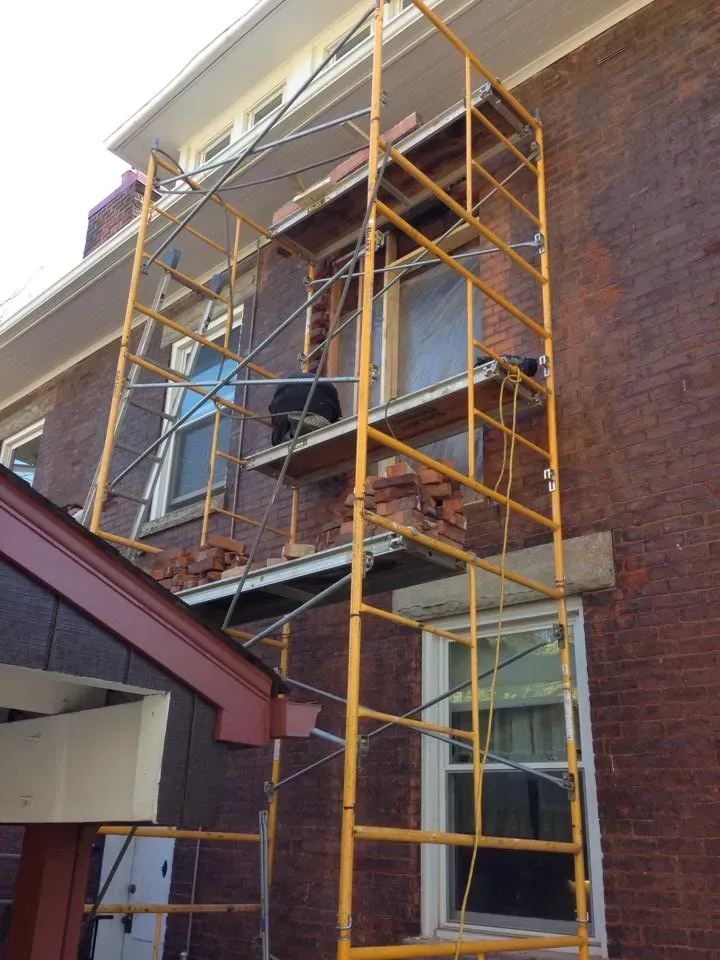 A yellow scaffolding is attached to the side of a brick building