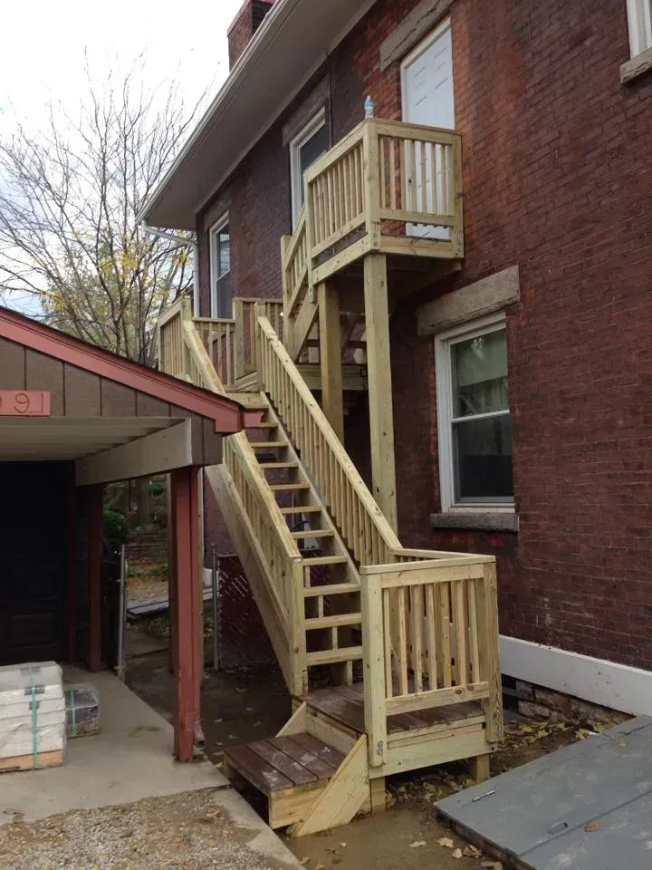 A wooden staircase is attached to the side of a brick building.