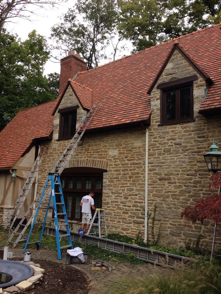 A man on a ladder is painting a stone house
