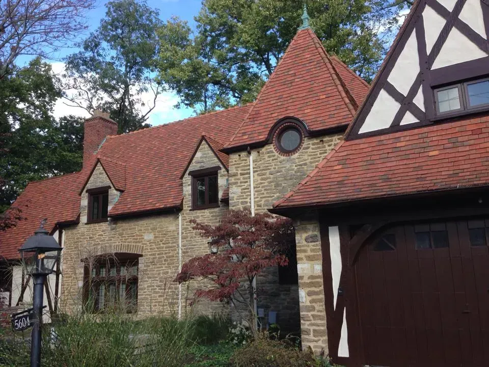 A large stone house with a red roof and a brown garage door.