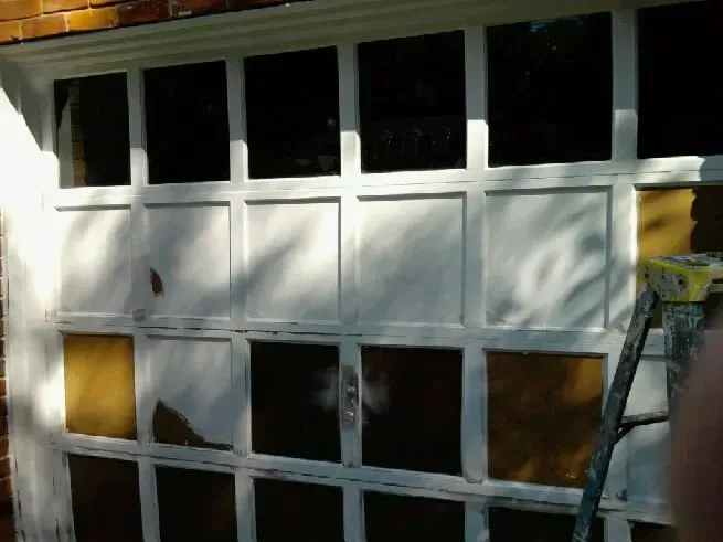 A white garage door with a yellow ladder in front of it