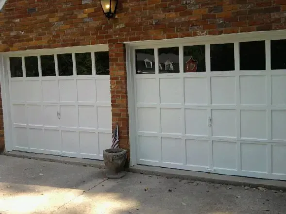 A pair of white garage doors on a brick building.
