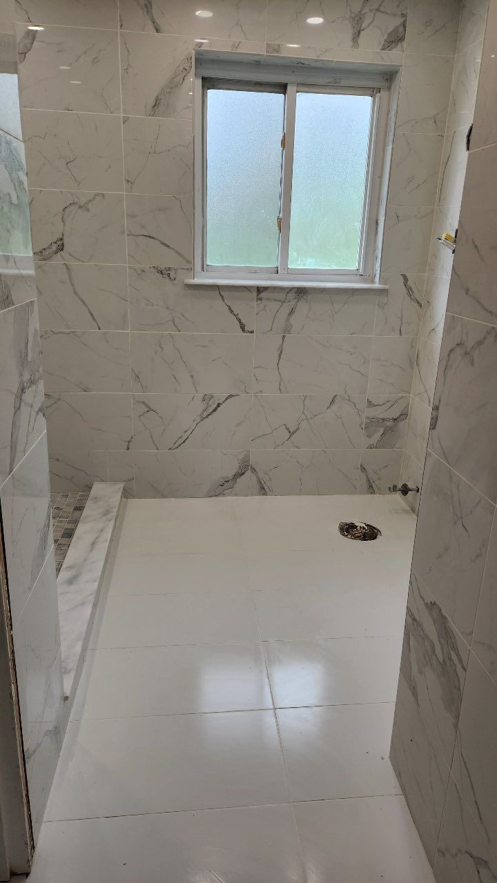 A bathroom with white tiles and a window.