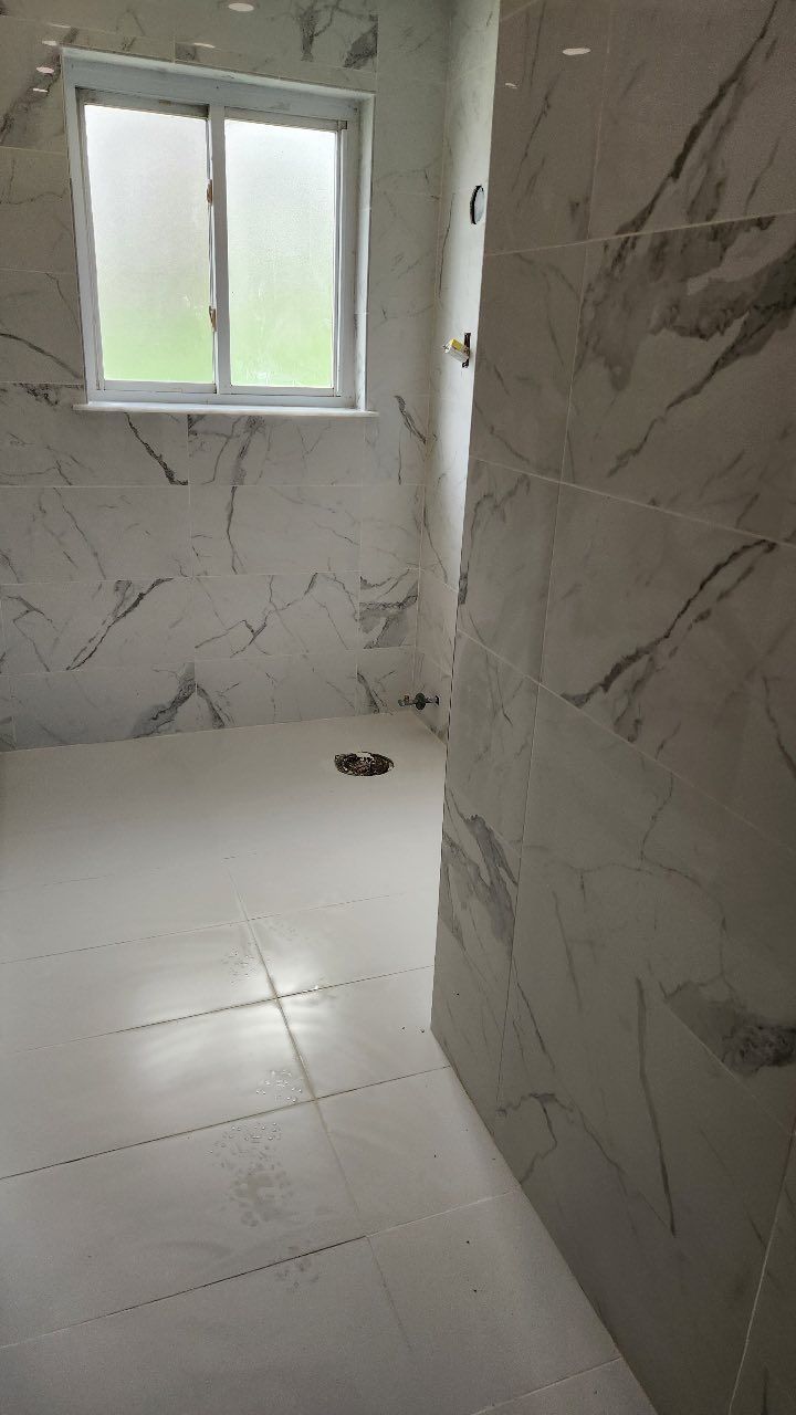 A bathroom with white tiles and marble walls and a window.