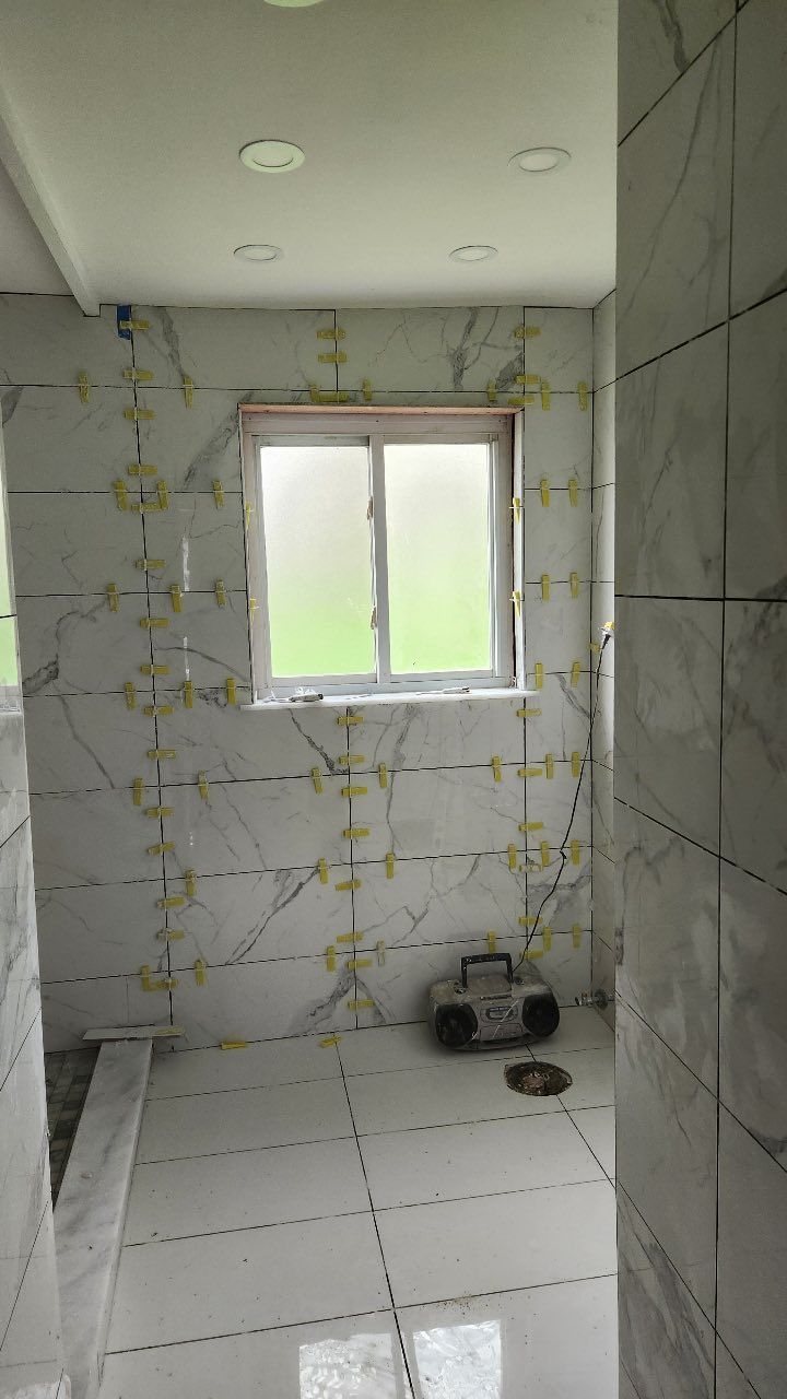 A bathroom under construction with a window and a radio on the floor.