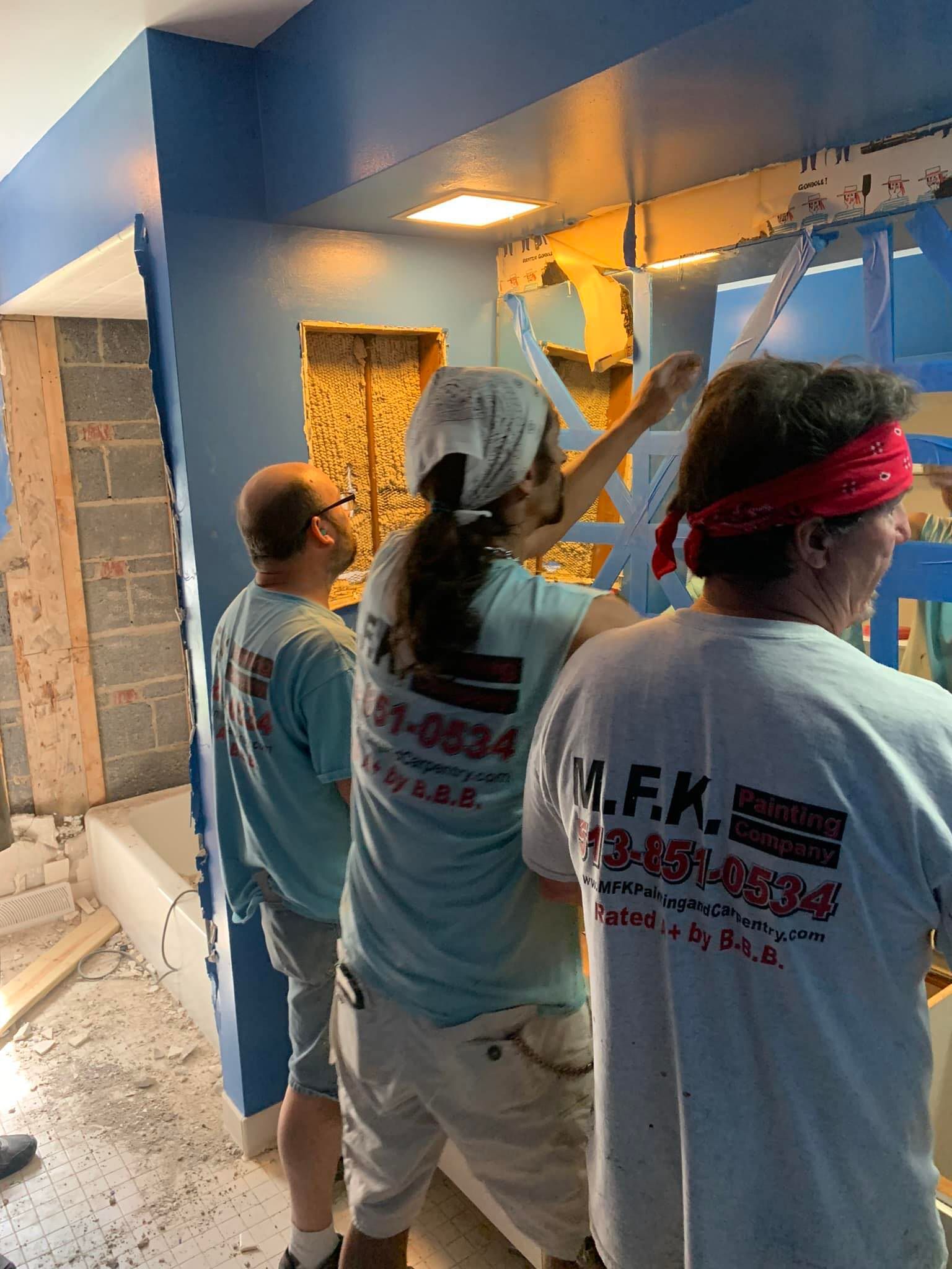 A group of people are painting a wall in a room.