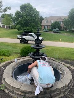 A man is working on a fountain in front of a house.