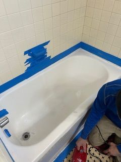 A person is cleaning a bathtub with a vacuum cleaner.