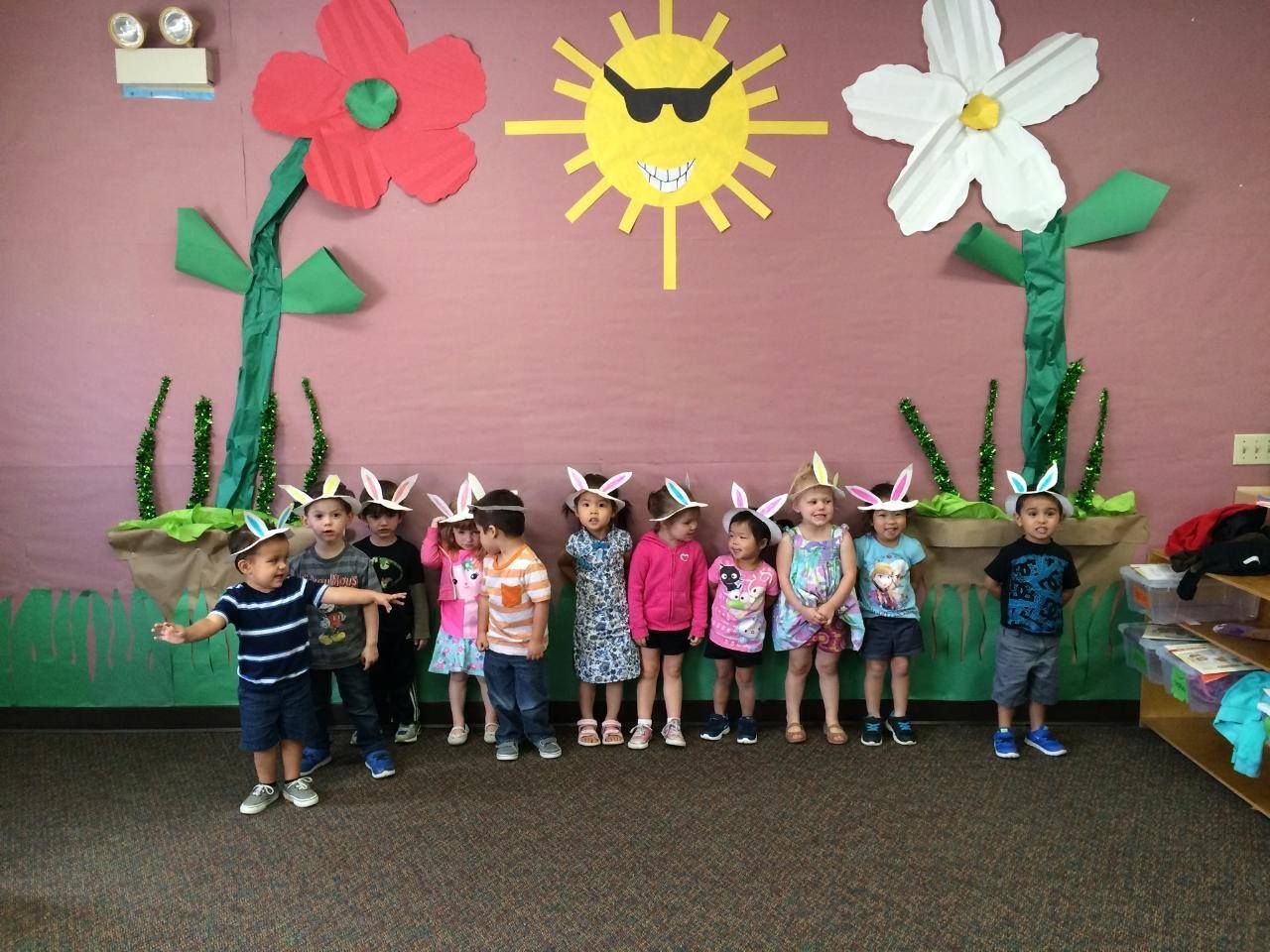 Children in bunny ears pose in front of flower decorations.