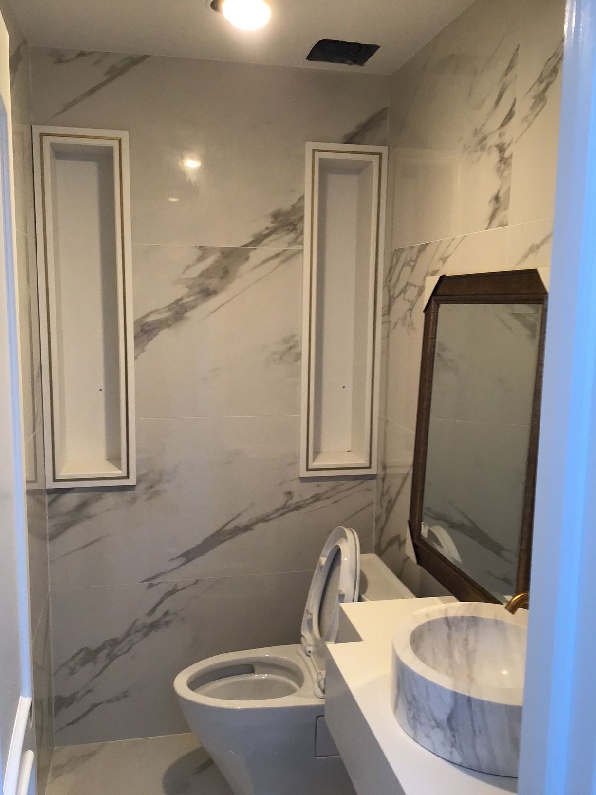 A bathroom with a toilet , sink and mirror