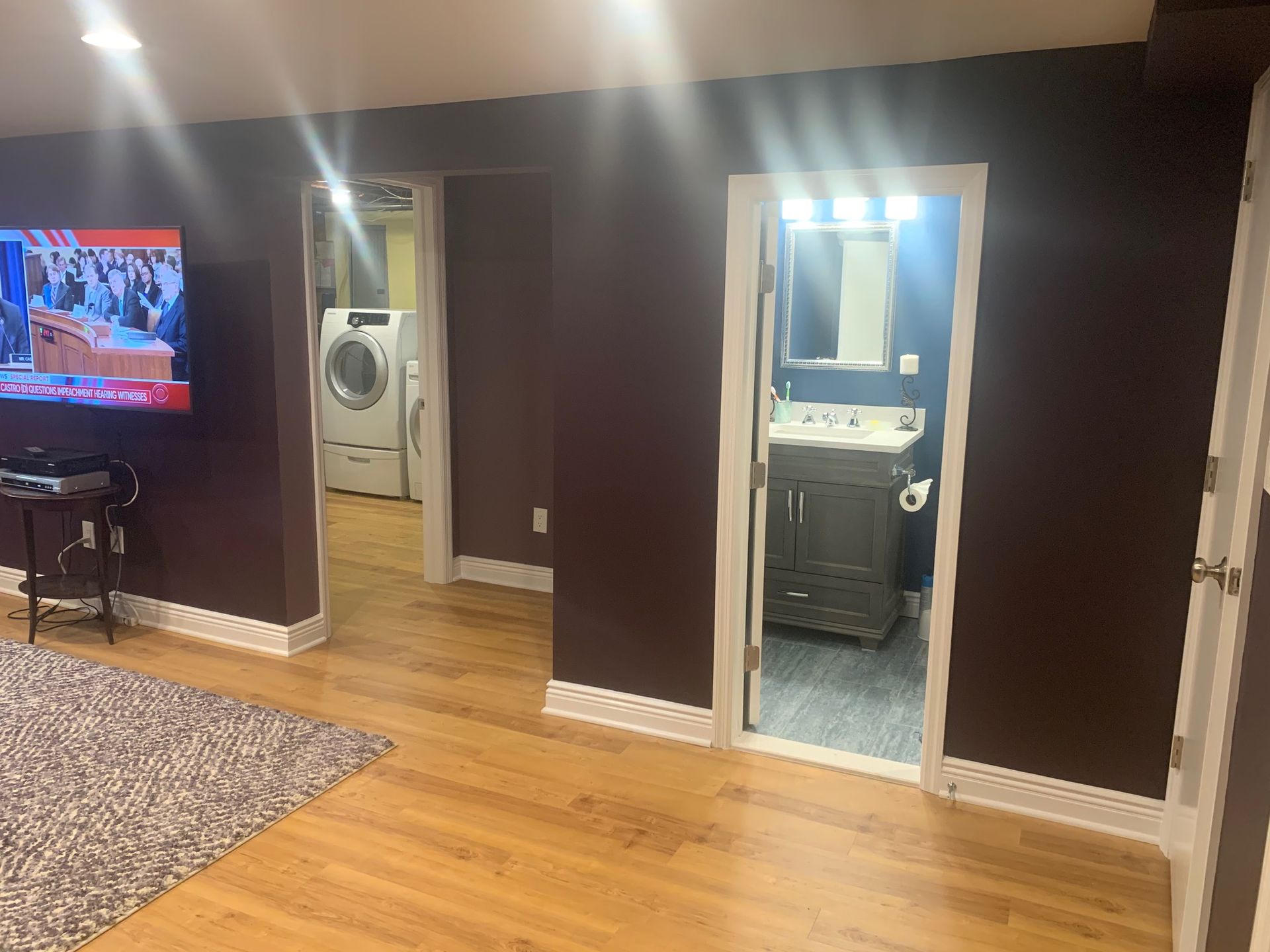 A basement with a washer and dryer , a bathroom , and a television.