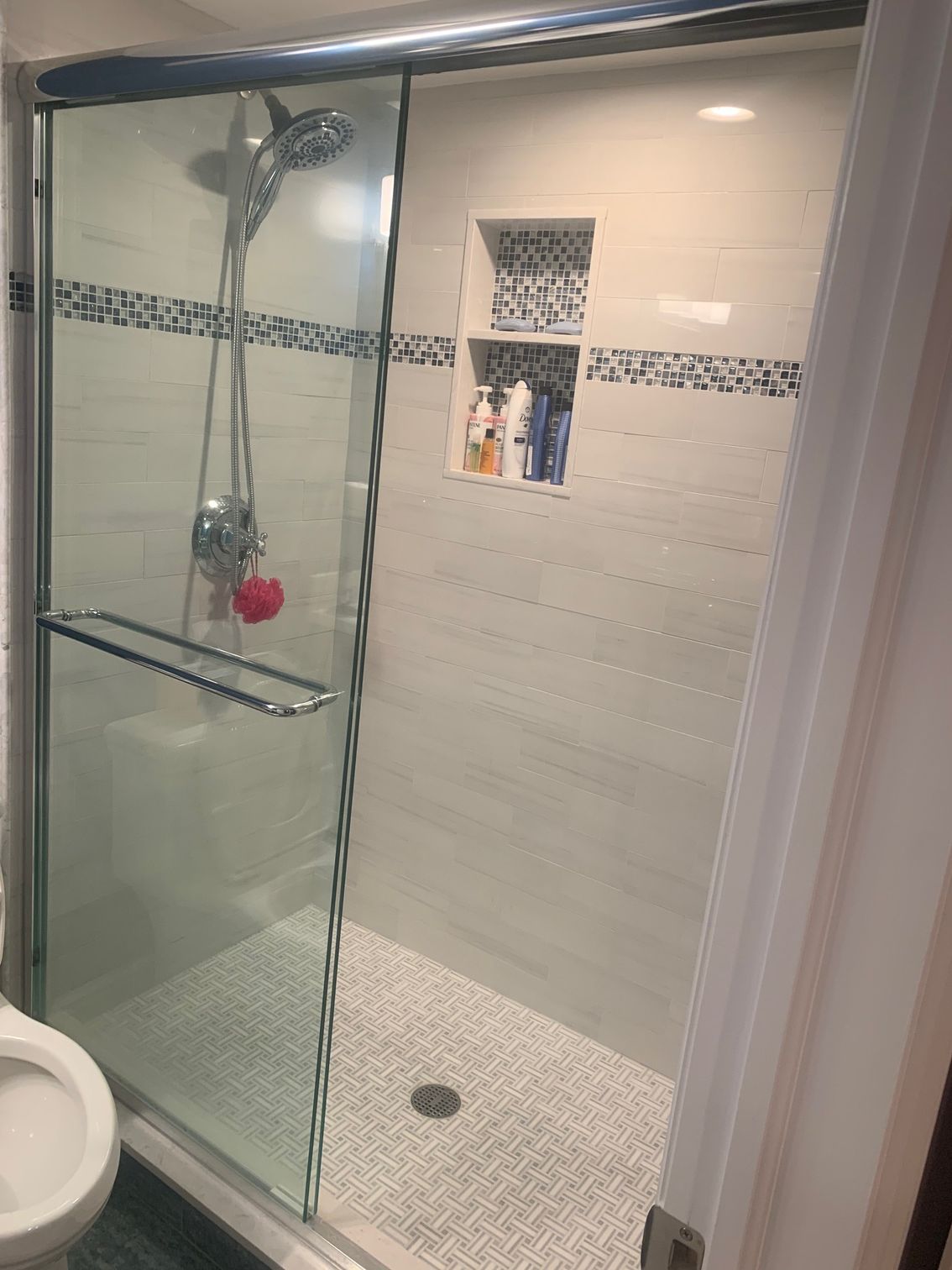 A bathroom with a sliding glass shower door and a toilet.