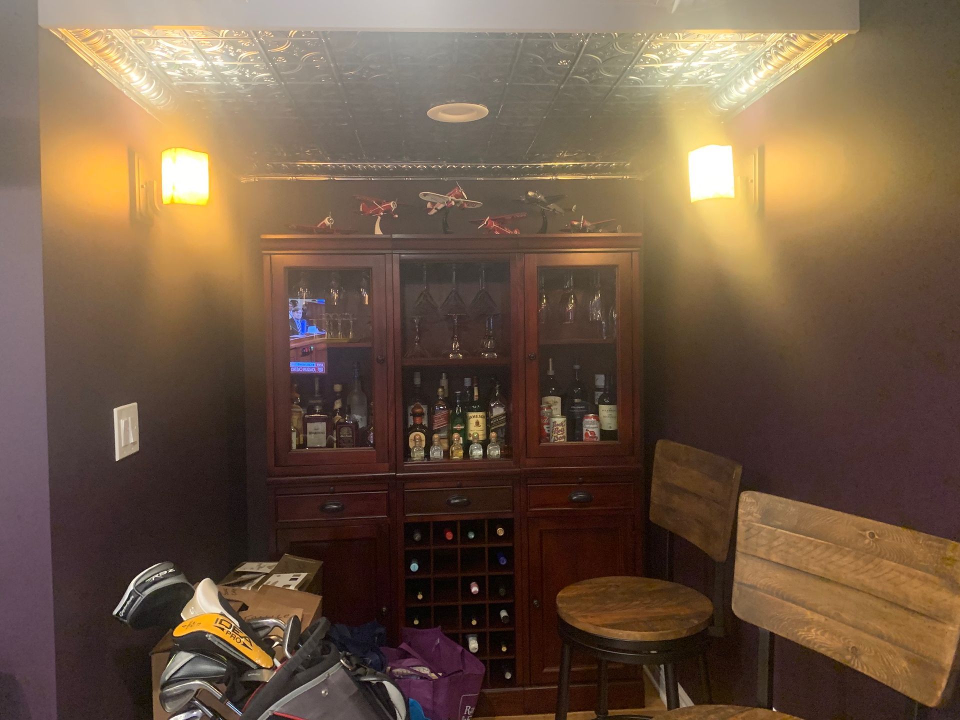 A room with purple walls and a bar with a lot of bottles on it.