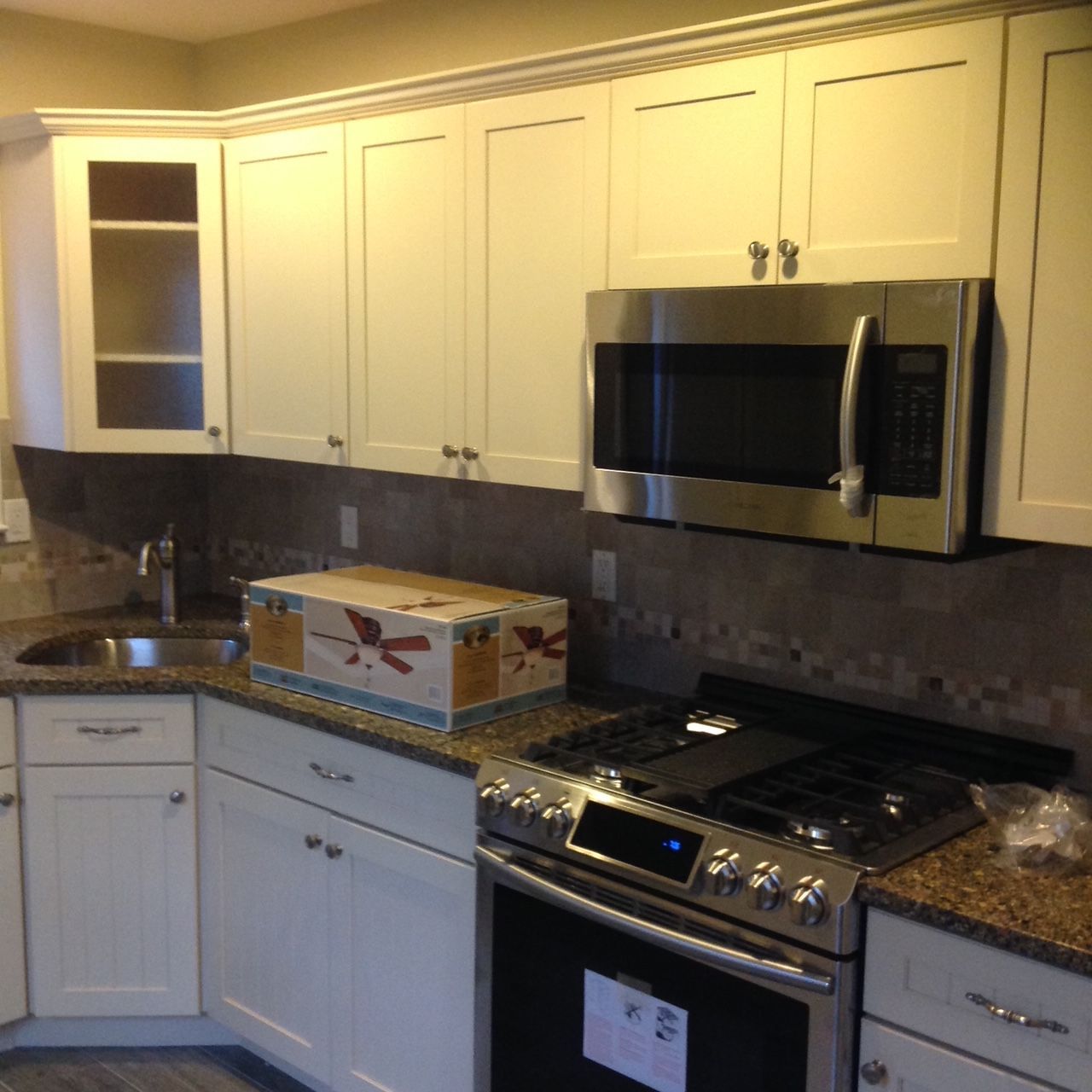 A kitchen with white cabinets a stove and a microwave