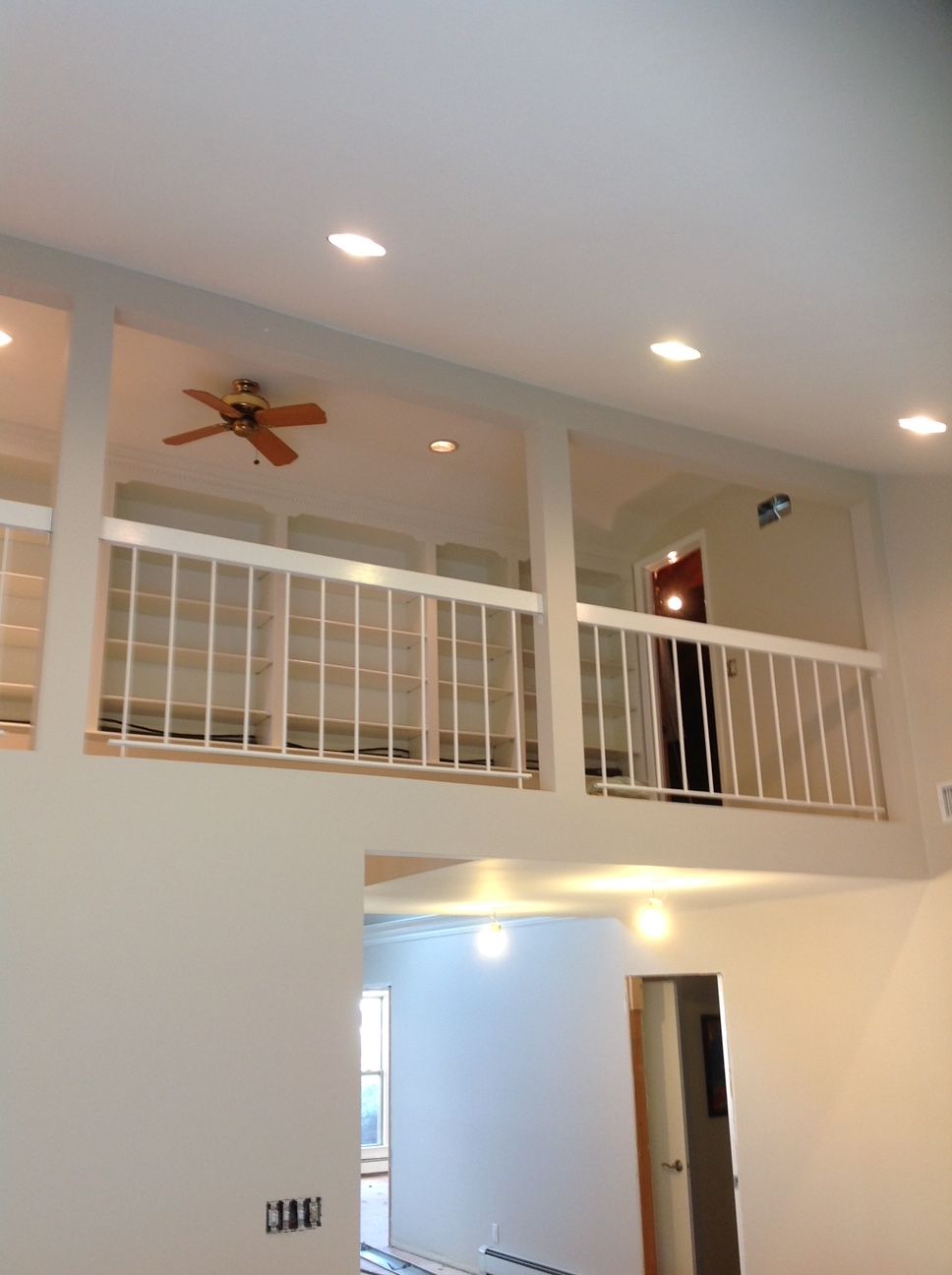 A room with a balcony and a ceiling fan