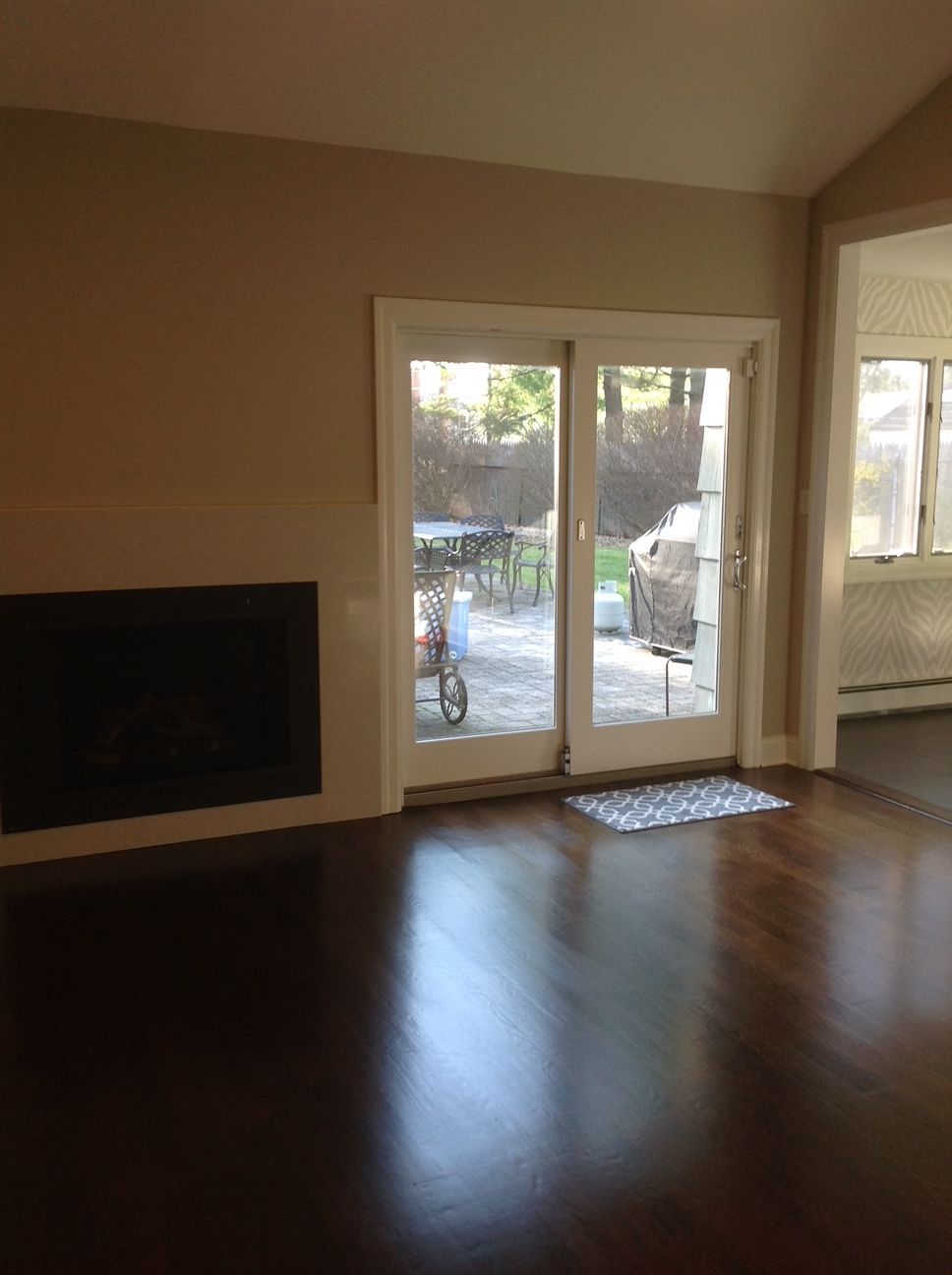 An empty living room with hardwood floors and sliding glass doors leading to a patio.