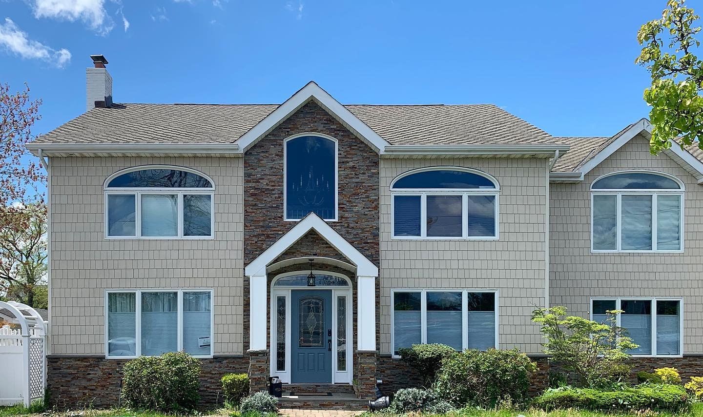 A large house with a lot of windows and a roof on a sunny day.