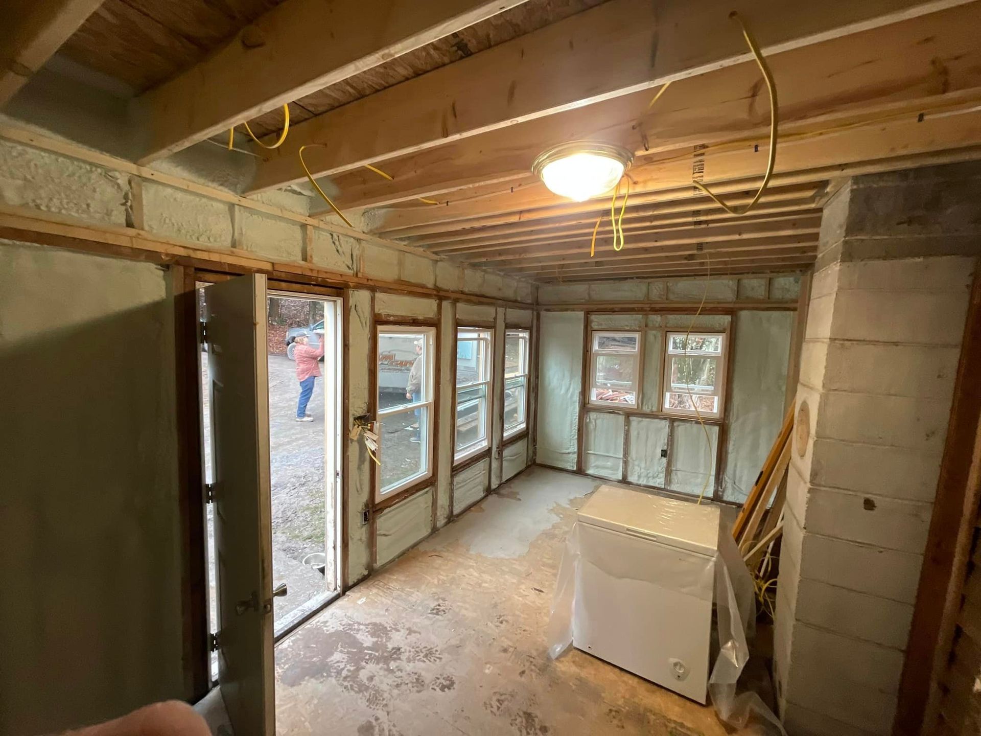 A man is spraying insulation on a garage door.