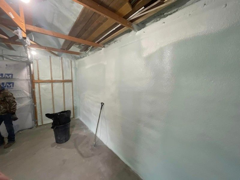 A man is standing in a room with a large white wall.