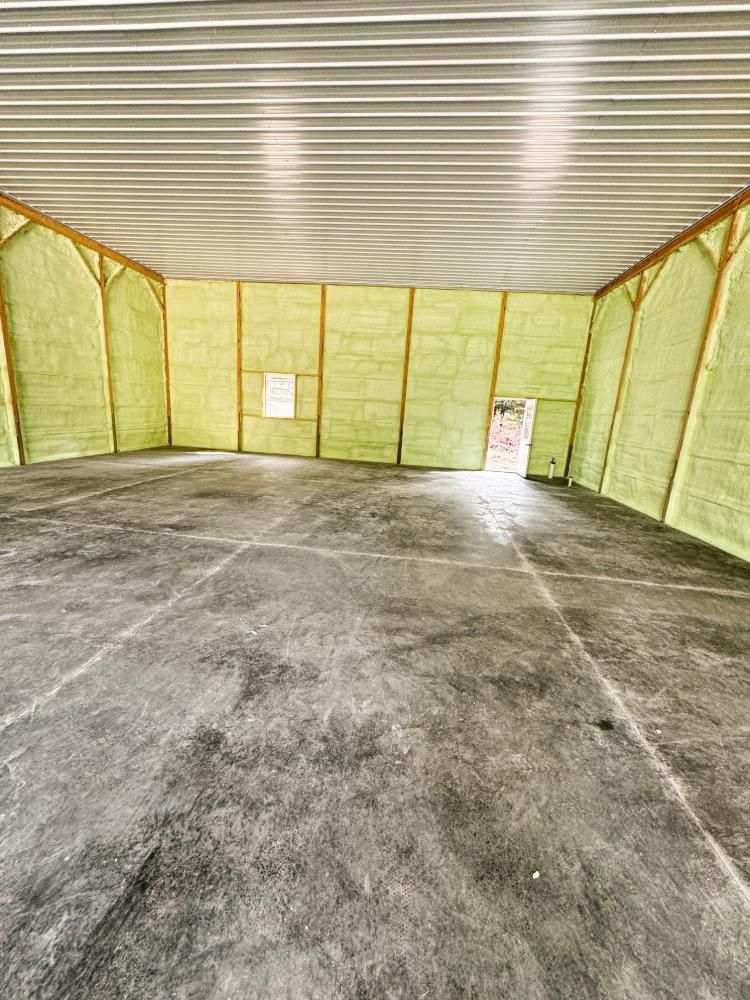 A large empty room with a concrete floor and walls covered in insulation.