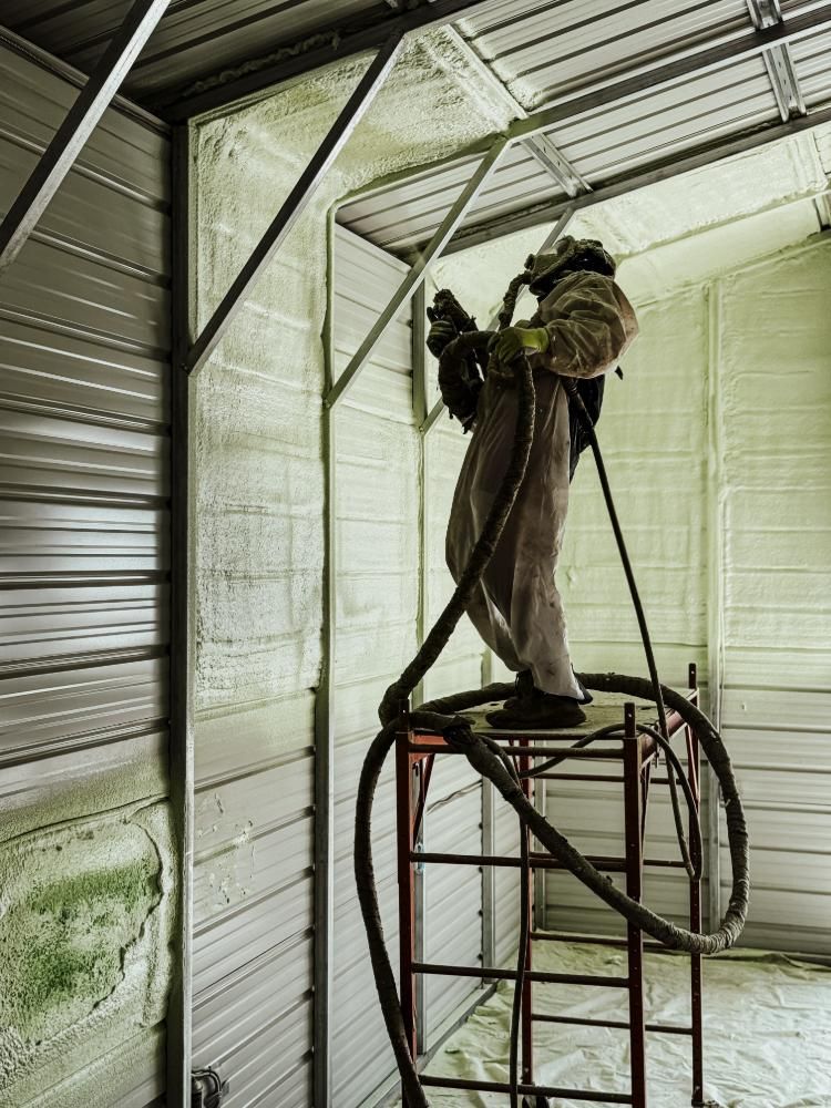 A man is spraying insulation on a garage door.