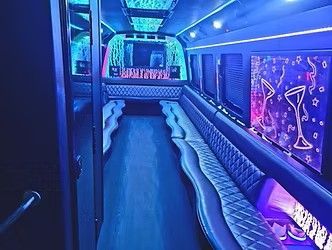 Blue-lit luxury bus interior with neon side panels and plush seating running along the aisle