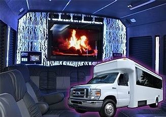White shuttle van inside a blue-lit luxury lounge with a large fireplace screen and striped seating