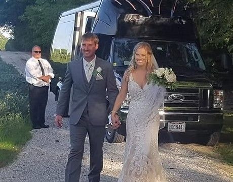 Bride and groom walking beside a black limousine at an outdoor wedding venue