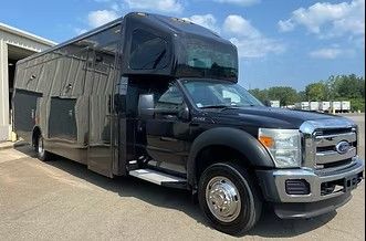 Black pickup truck with a large gray camper attachment parked on a lot under a blue sky