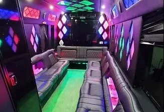 Empty limousine interior with neon purple, blue, and green lights and gray leather seats