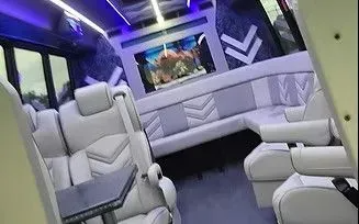 Luxury white bus interior with LED lights, plush seats, and a fish tank display at the front