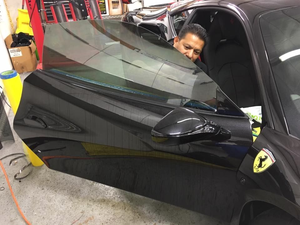 a man is peeking out of the window of a black sports car .