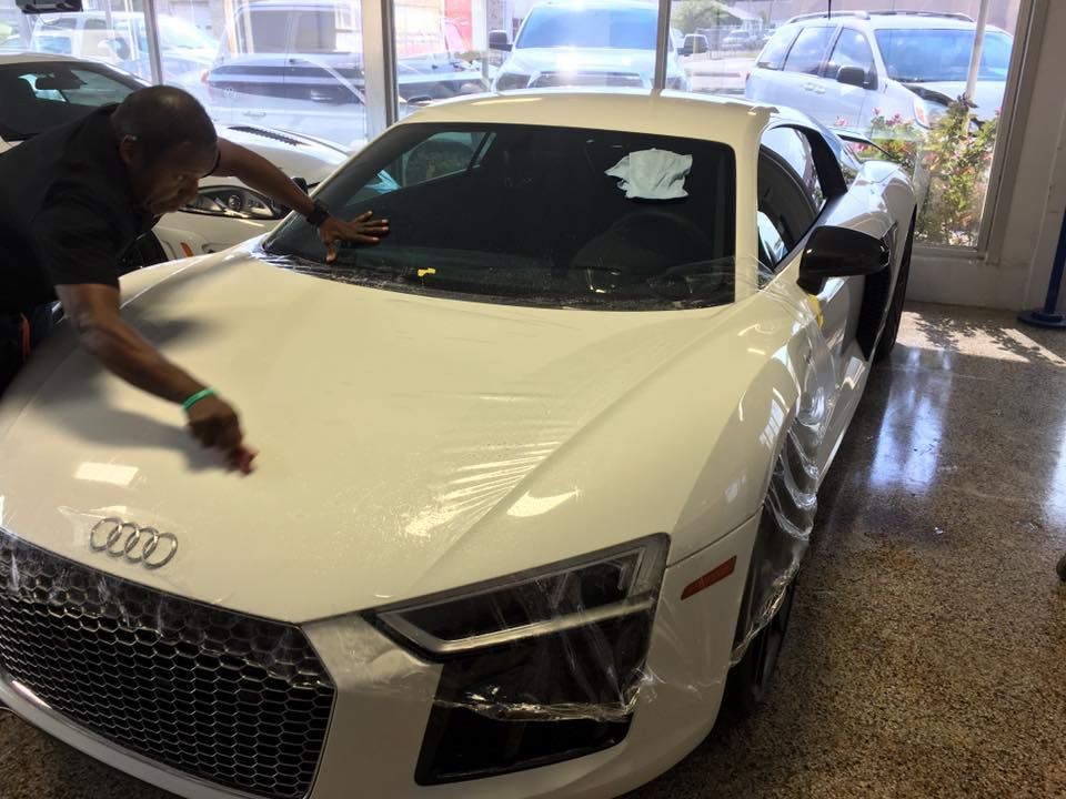 a man is working on a white audi r8 in a showroom .