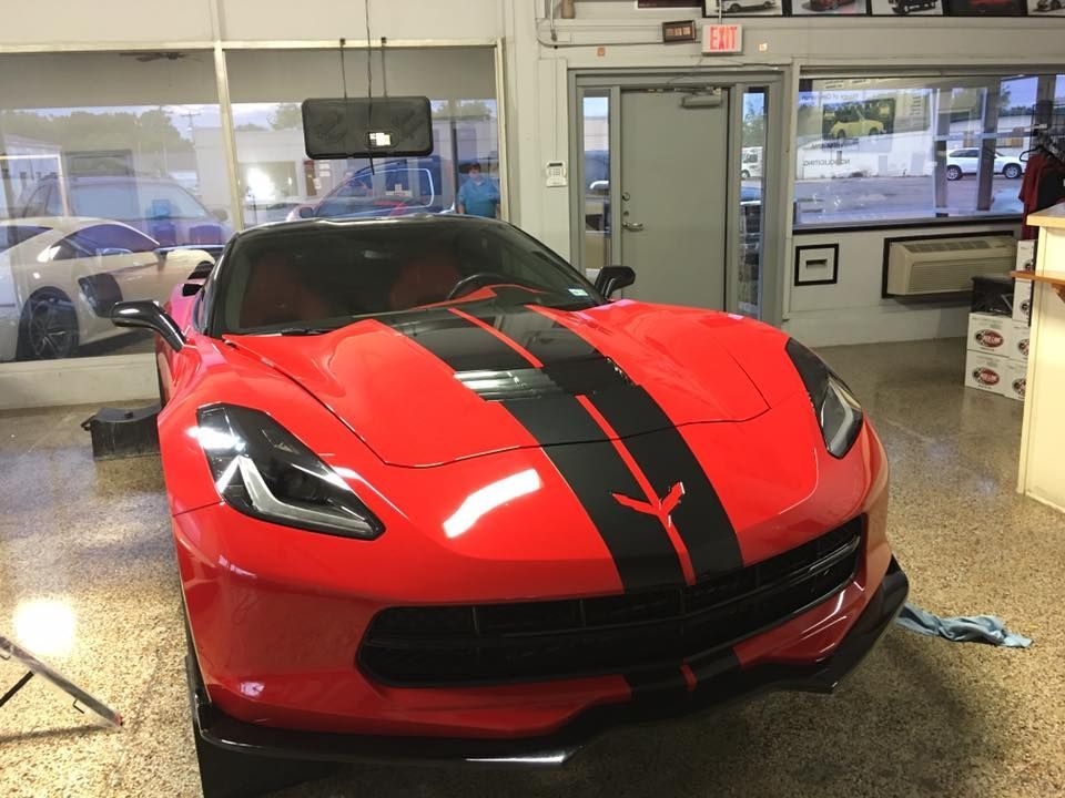 a red sports car with black stripes is parked in a garage .